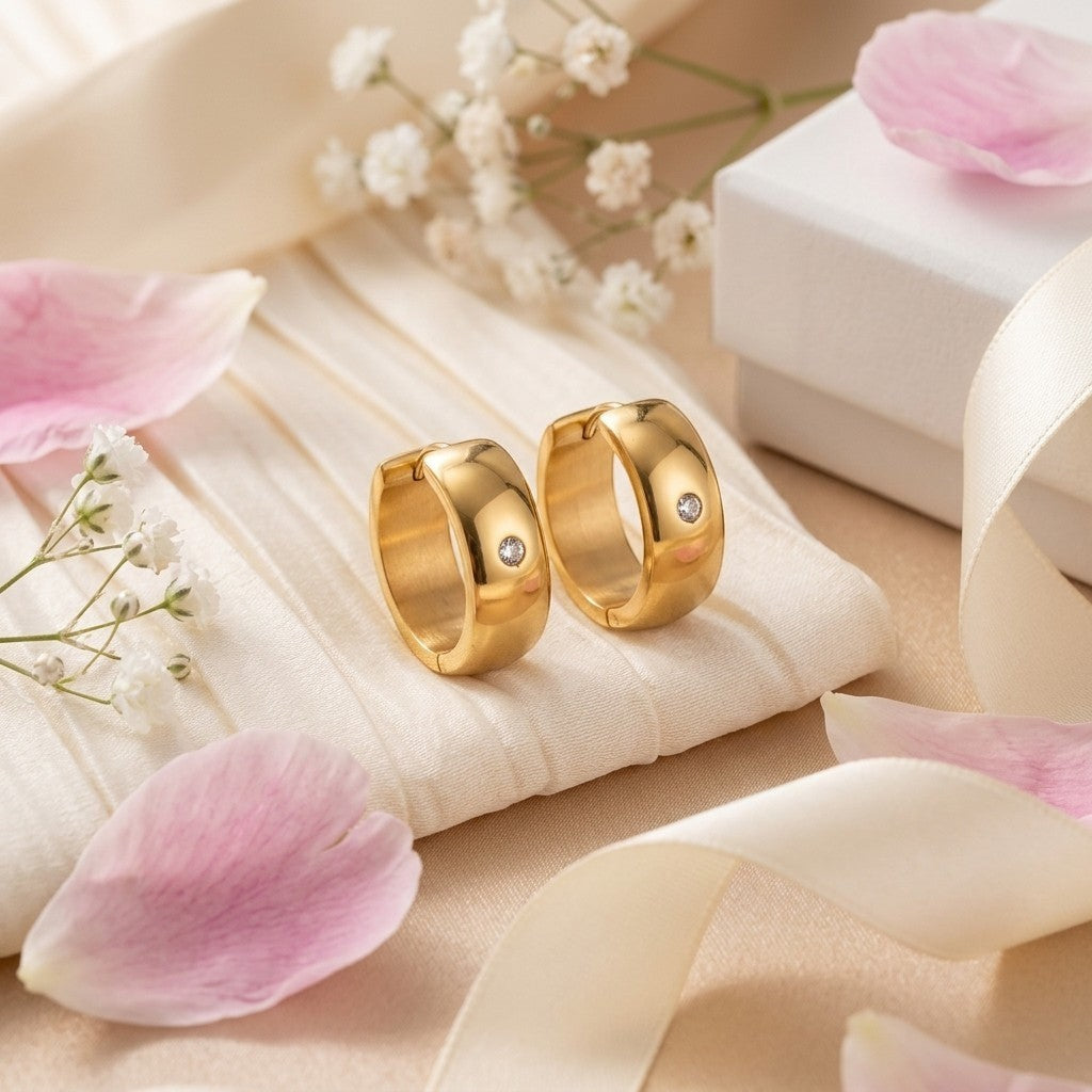 Aramat Jewels gold-tone stainless steel huggie hoop earrings with a central cubic zirconia stone.