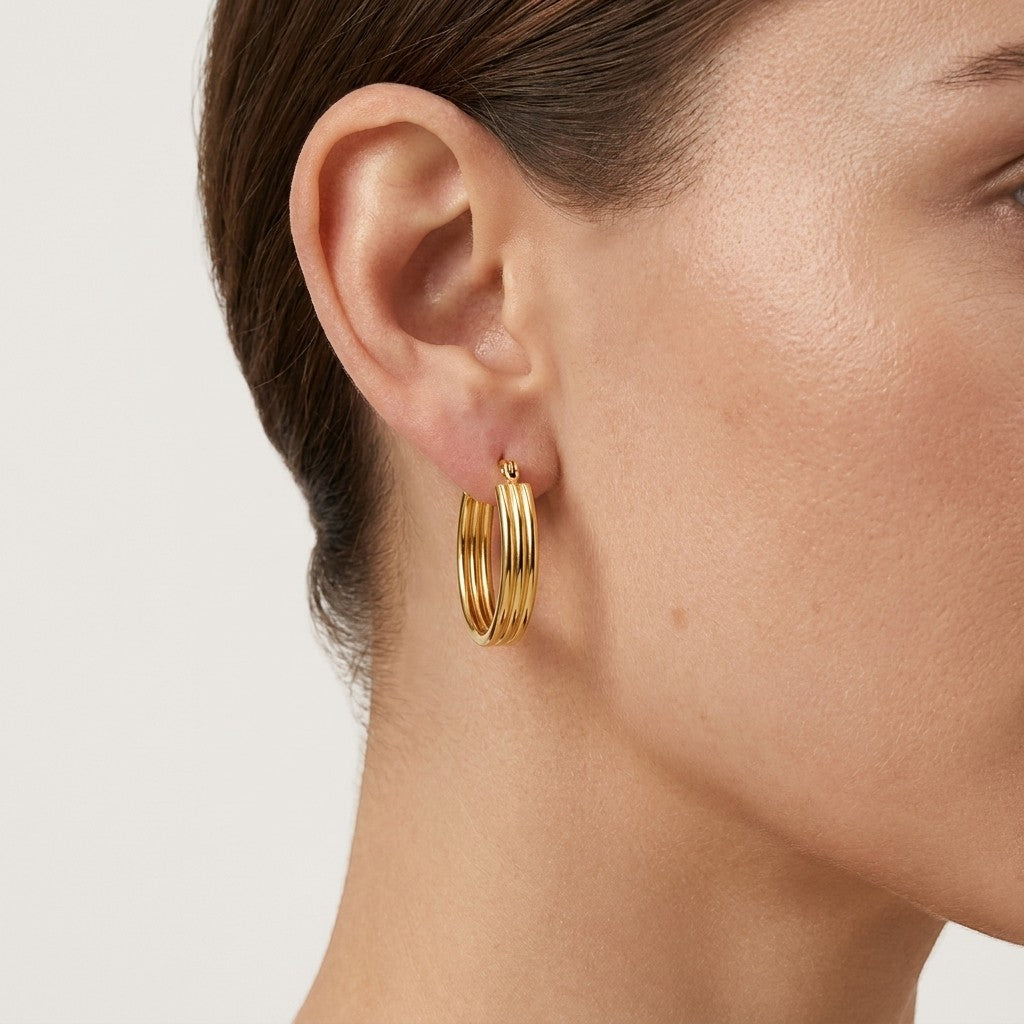 Aramat Jewels gold oval hoop earrings with a ribbed texture, 26mm size, worn by a model.