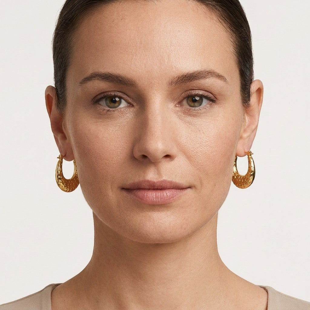 Aramat Jewels gold oval hoop earrings with a subtle textured pattern, 25x19mm, made of stainless steel.
