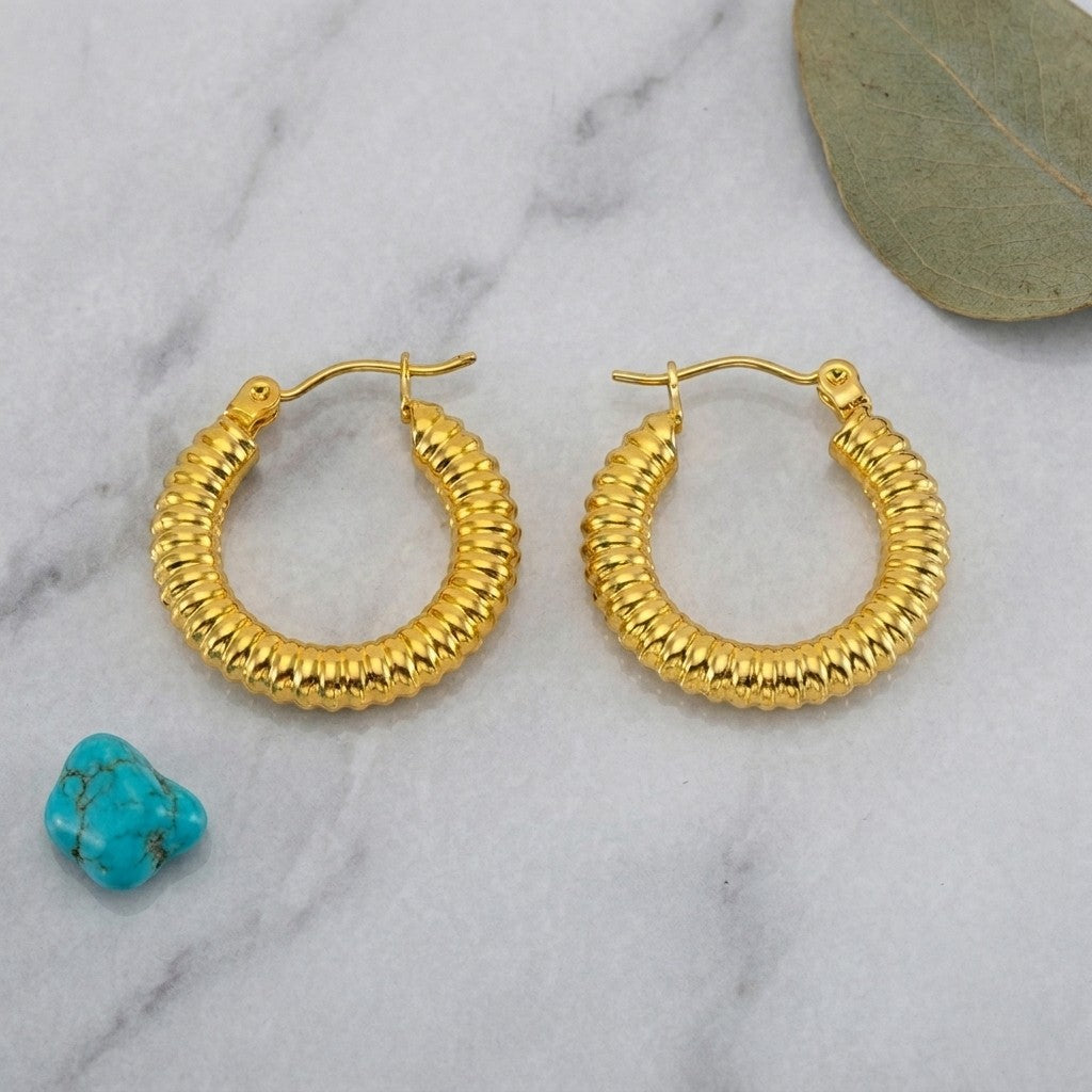 Aramat Jewels gold-colored stainless steel hoop earrings with a ribbed stripe pattern, 22x4mm, featuring a hinge closure.