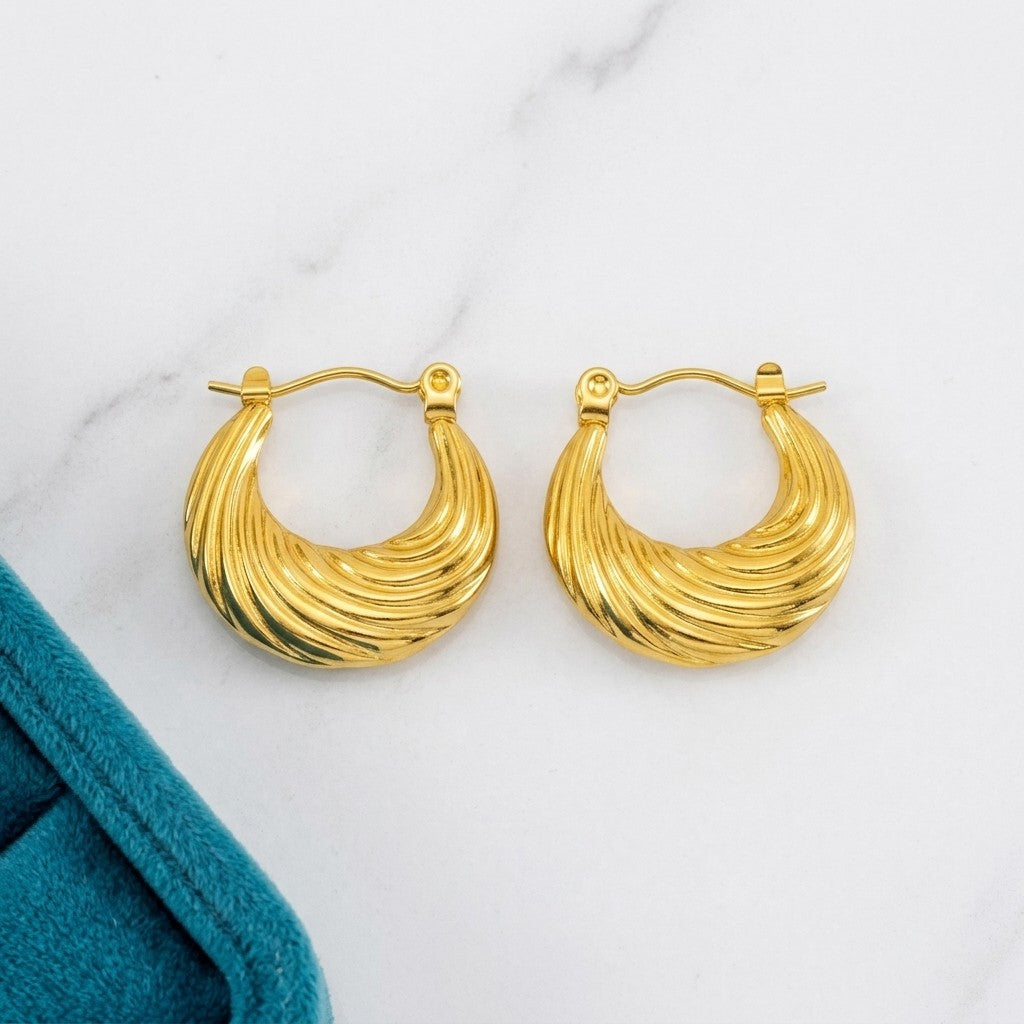 Aramat Jewels gold-tone stainless steel hoop earrings with a curved, ribbed stripe design, 20mm diameter.