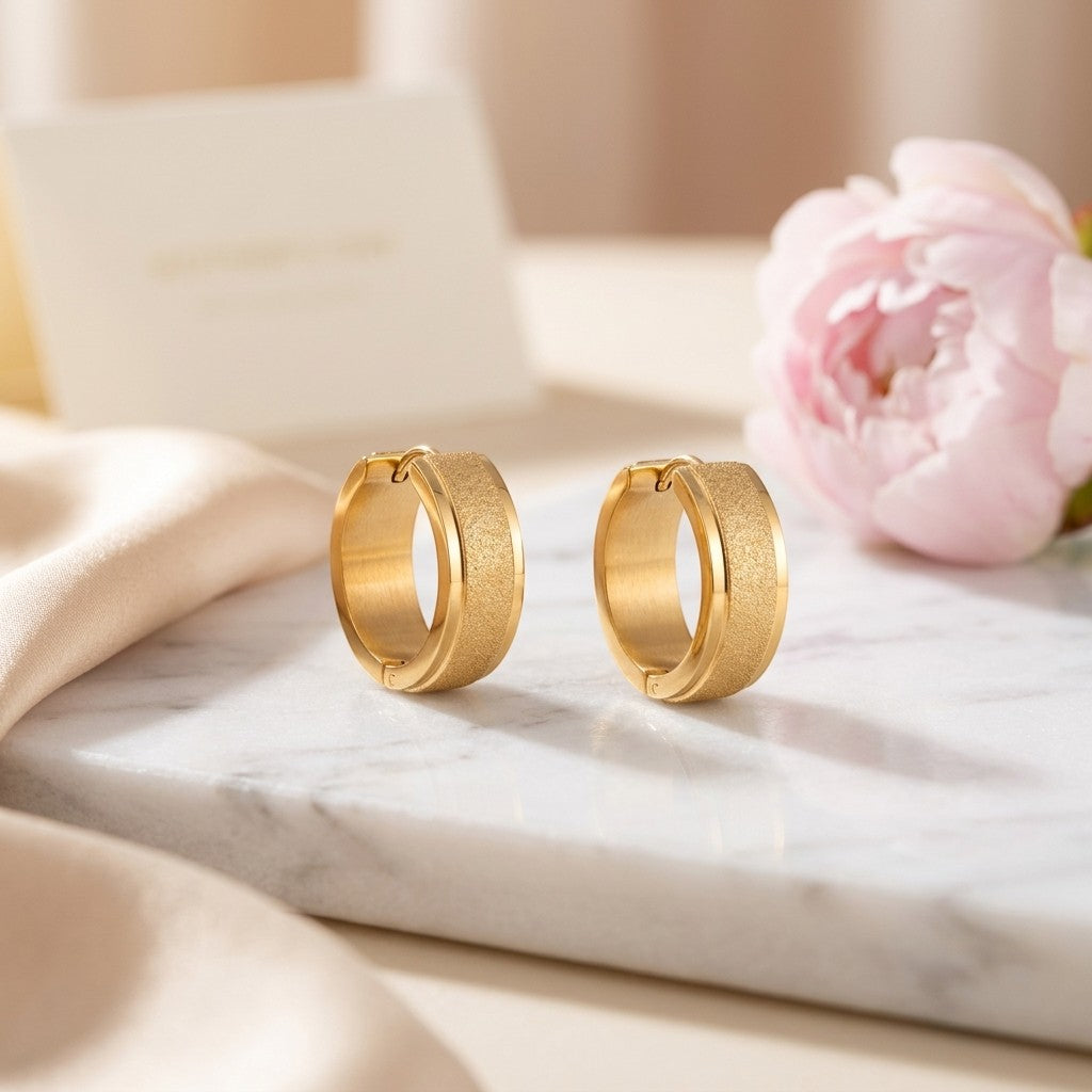 Aramat Jewels gold-tone stainless steel hoop earrings with sandblasted texture, 13mm or 20mm diameter.