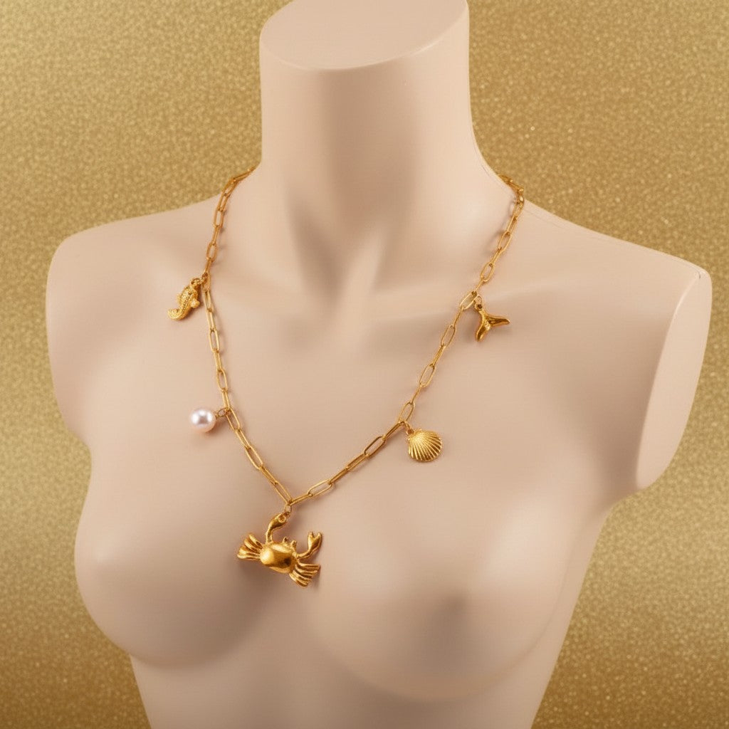 Aramat Jewels gold-tone stainless steel necklace with sea-themed charms: crab, pearl, fish, shell, and whale tail. 45 cm.