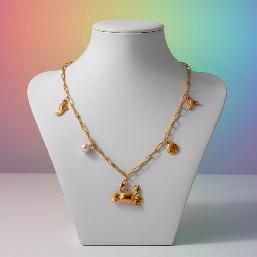 Aramat Jewels gold-tone stainless steel necklace with sea-themed charms: crab, pearl, fish, shell, and whale tail.