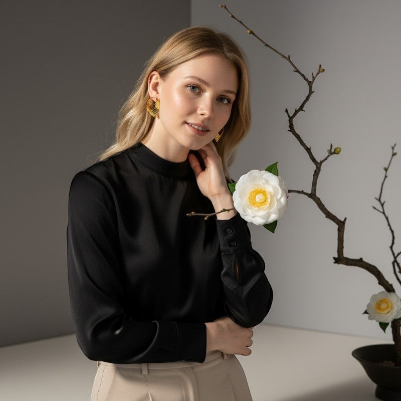 Aramat Jewels gold-colored square stainless steel hoop earrings with 6 stacked hoops, worn by a blonde model in a black blouse.