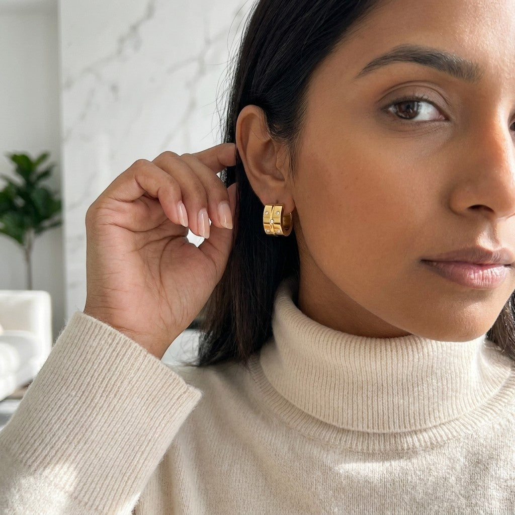 Aramat Jewels gold-tone stainless steel hoop earrings with 5 small cubic zirconia stones, worn by a woman.