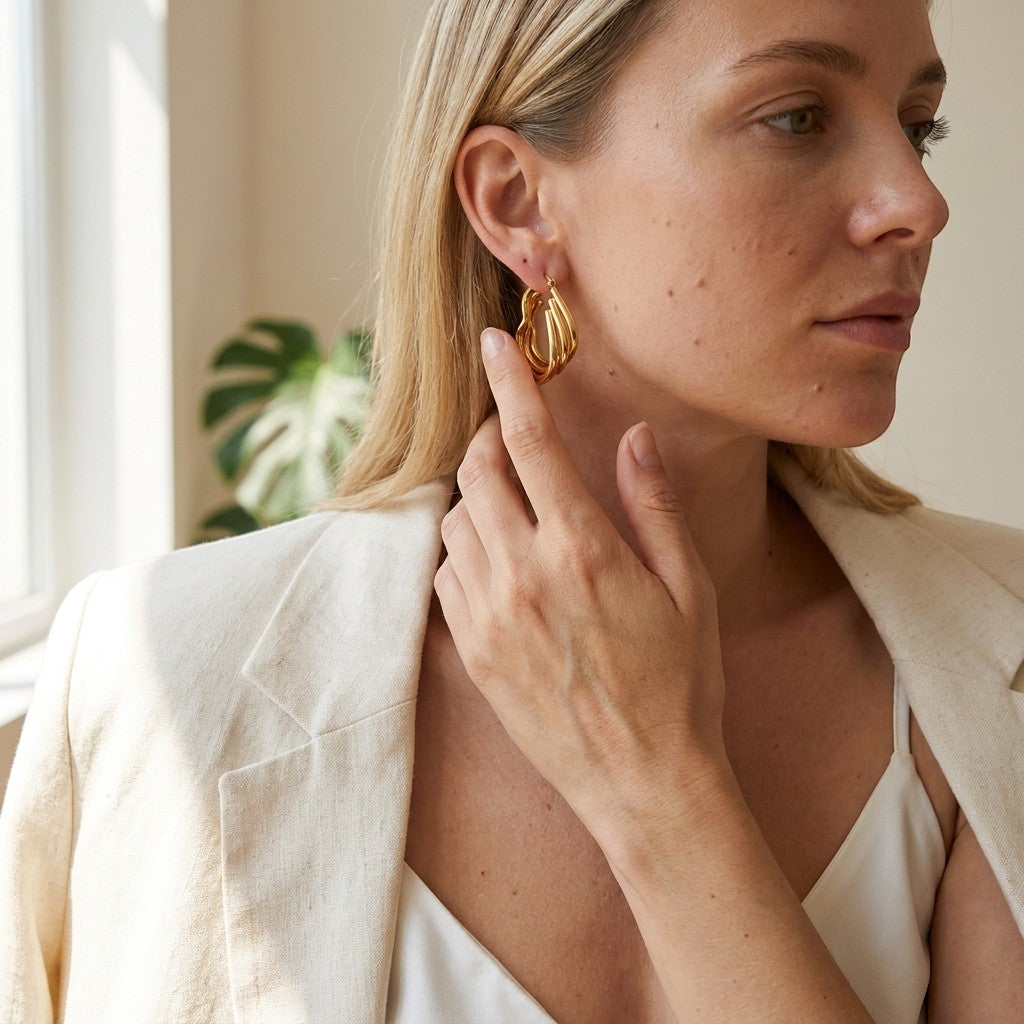Aramat Jewels gold-tone triple heart-shaped hoop earrings with a layered design, worn by a woman.