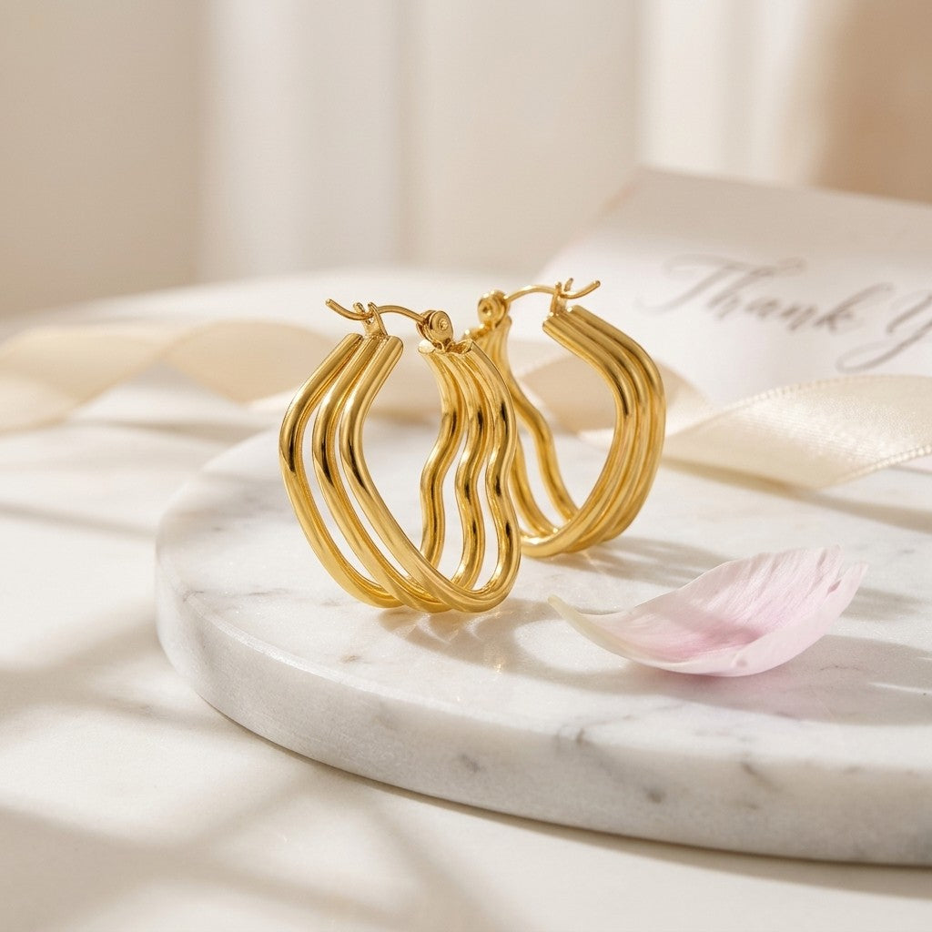 Aramat Jewels gold-tone triple heart hoop earrings made of stainless steel, 25mm high.