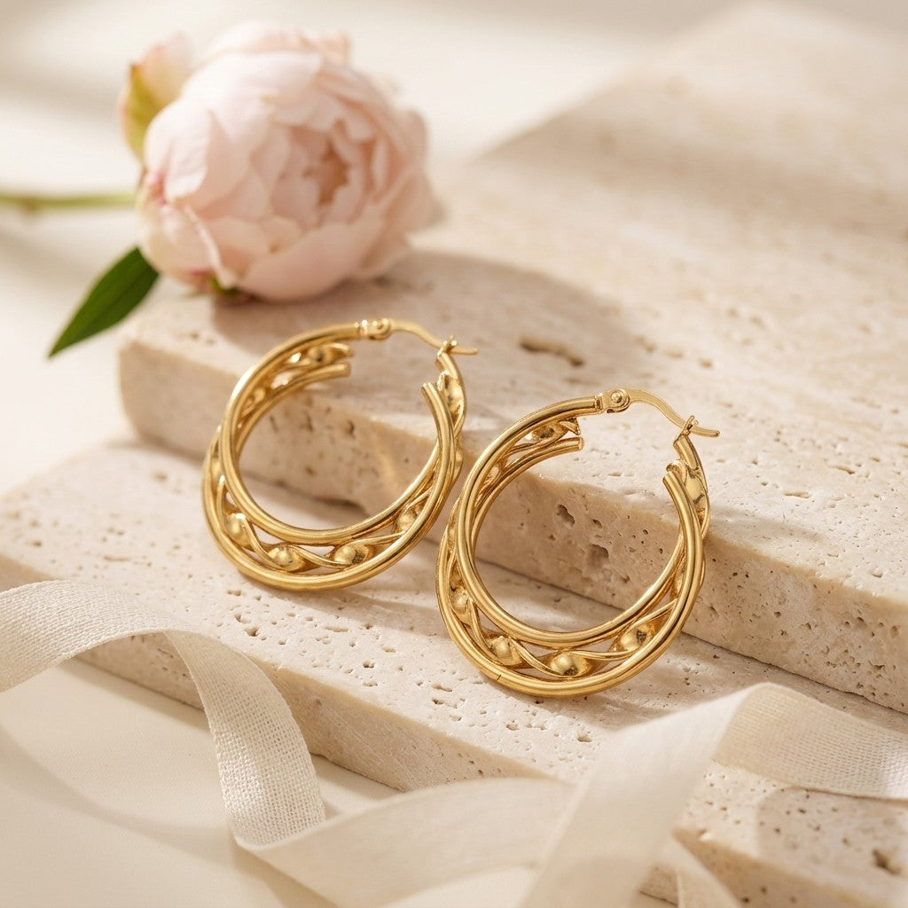 Aramat Jewels gold-tone stainless steel triple hoop earrings with a twisted design and beaded accents, 25x7mm.