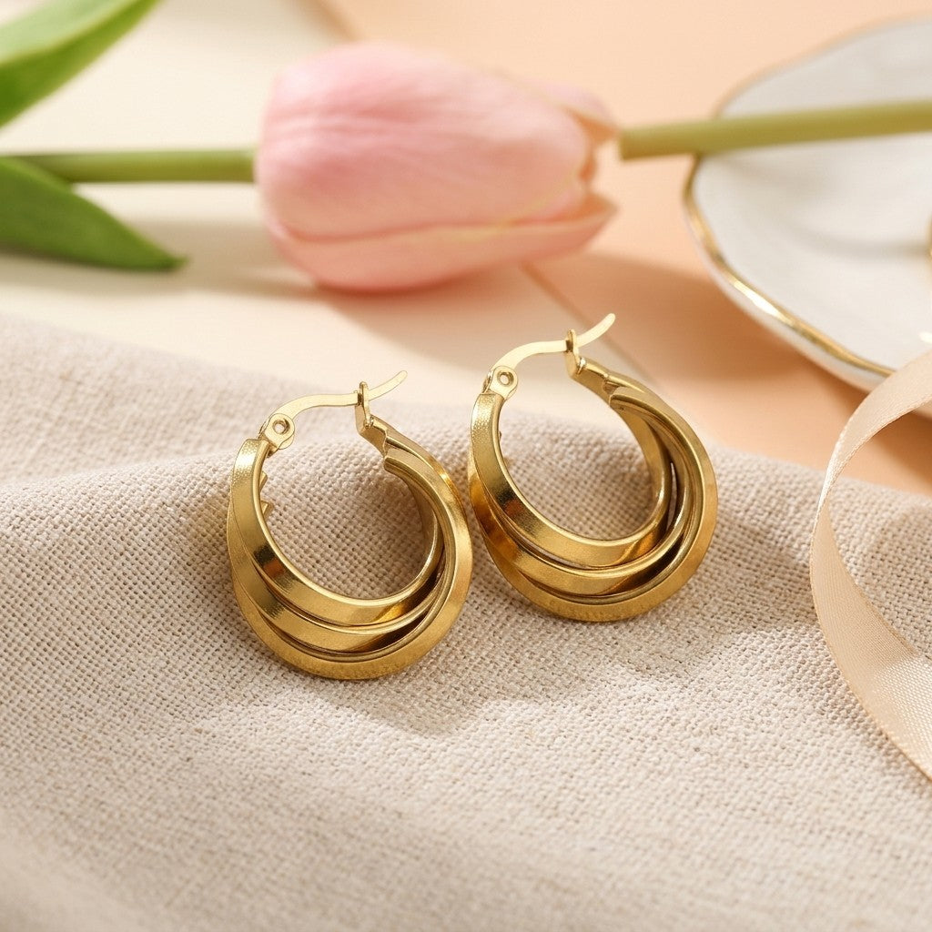 Aramat Jewels gold-tone stainless steel triple hoop earrings, 25x9mm, with a 3-in-1 layered design and hinge closure.