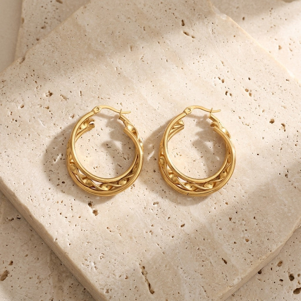 Aramat Jewels gold-tone stainless steel triple hoop earrings with a twisted design and beaded accents, 25x7mm.