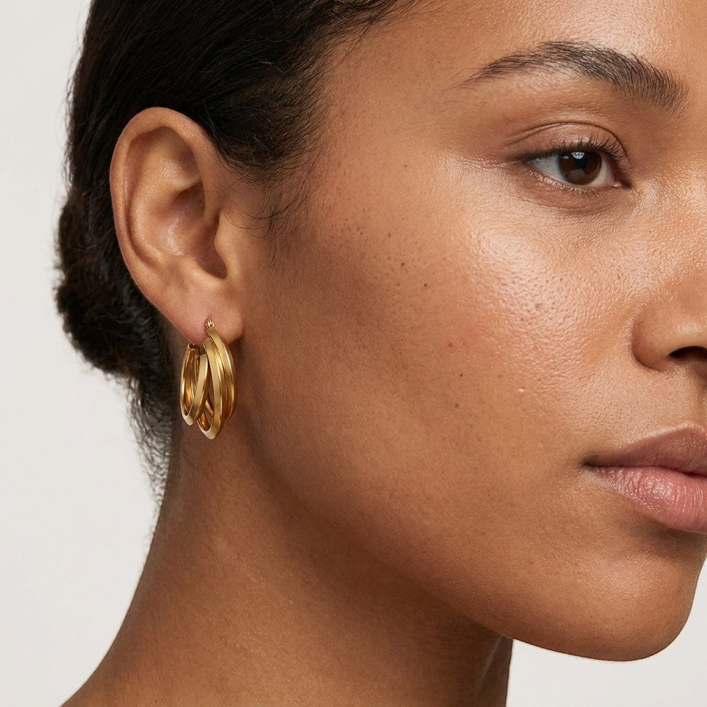Aramat Jewels gold-tone stainless steel triple hoop earrings with a crossed design, 25x7mm.