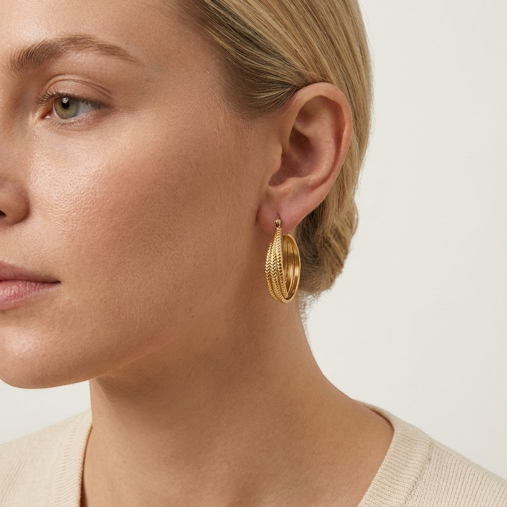 Aramat Jewels gold triple hoop earrings with chevron pattern detail, 20mm diameter, worn by a model.