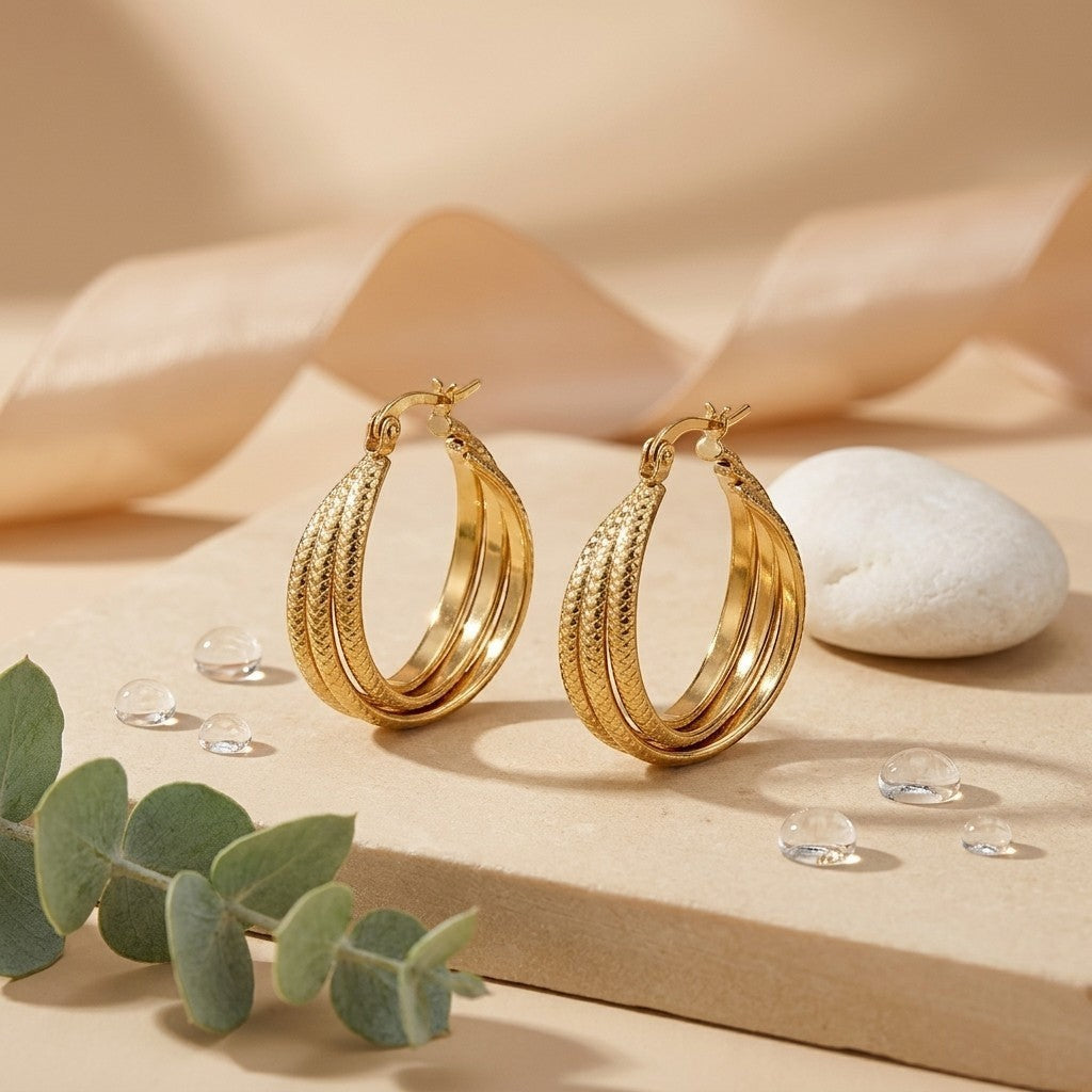 Aramat Jewels gold-tone triple hoop earrings with a textured stripe pattern, 25mm diameter, made of stainless steel.