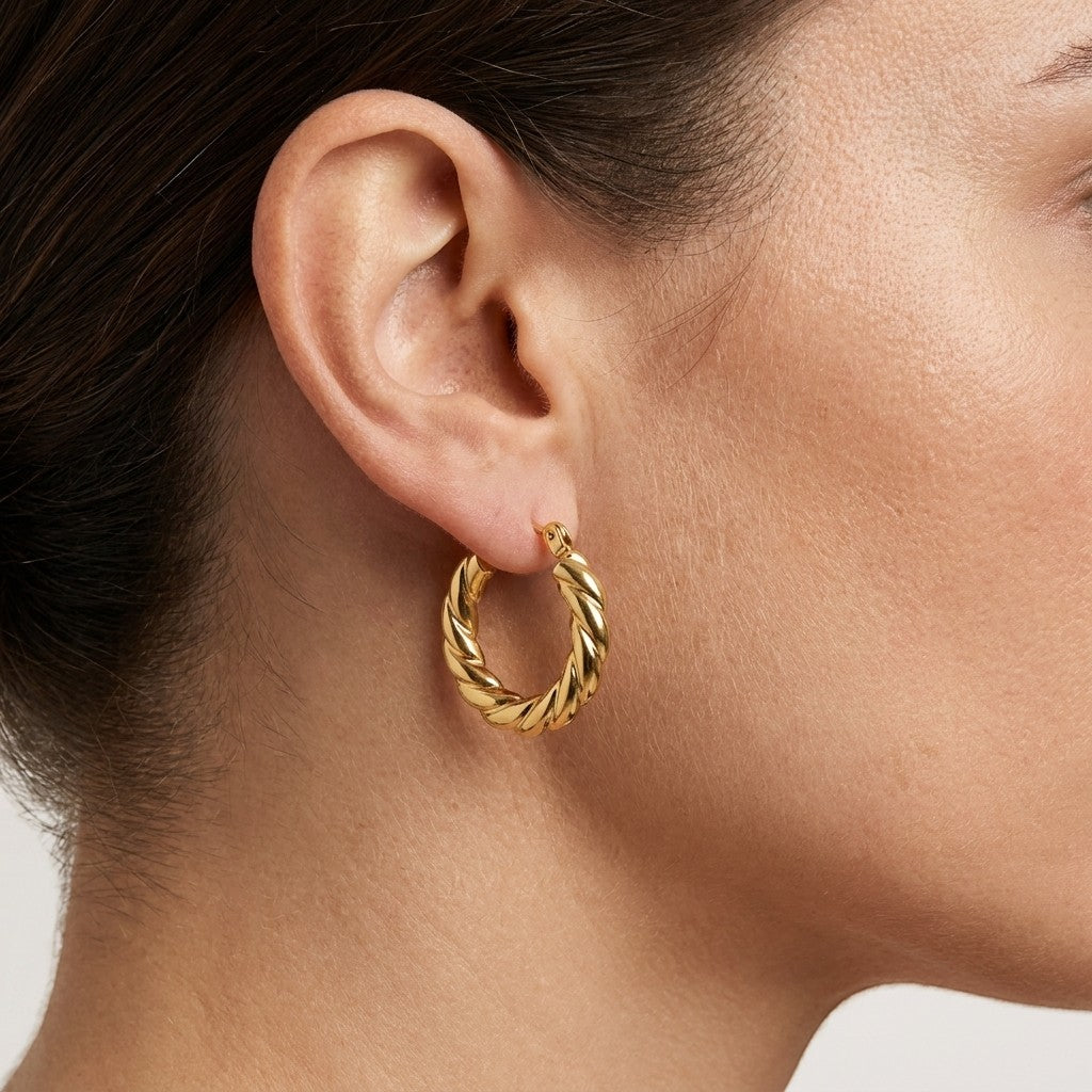 Aramat Jewels gold-colored stainless steel hoop earrings with a twisted rope design, 23mm diameter.