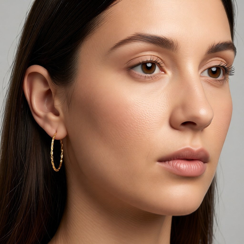 Aramat Jewels gold-colored twisted stainless steel hoop earrings, 30mm diameter, with a link motif and hinge closure.