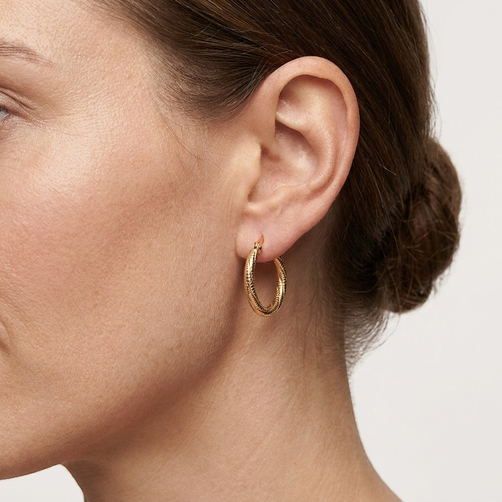Aramat Jewels gold-tone twisted, diamond-cut stainless steel hoop earrings, 20mm diameter, with a hinge closure.