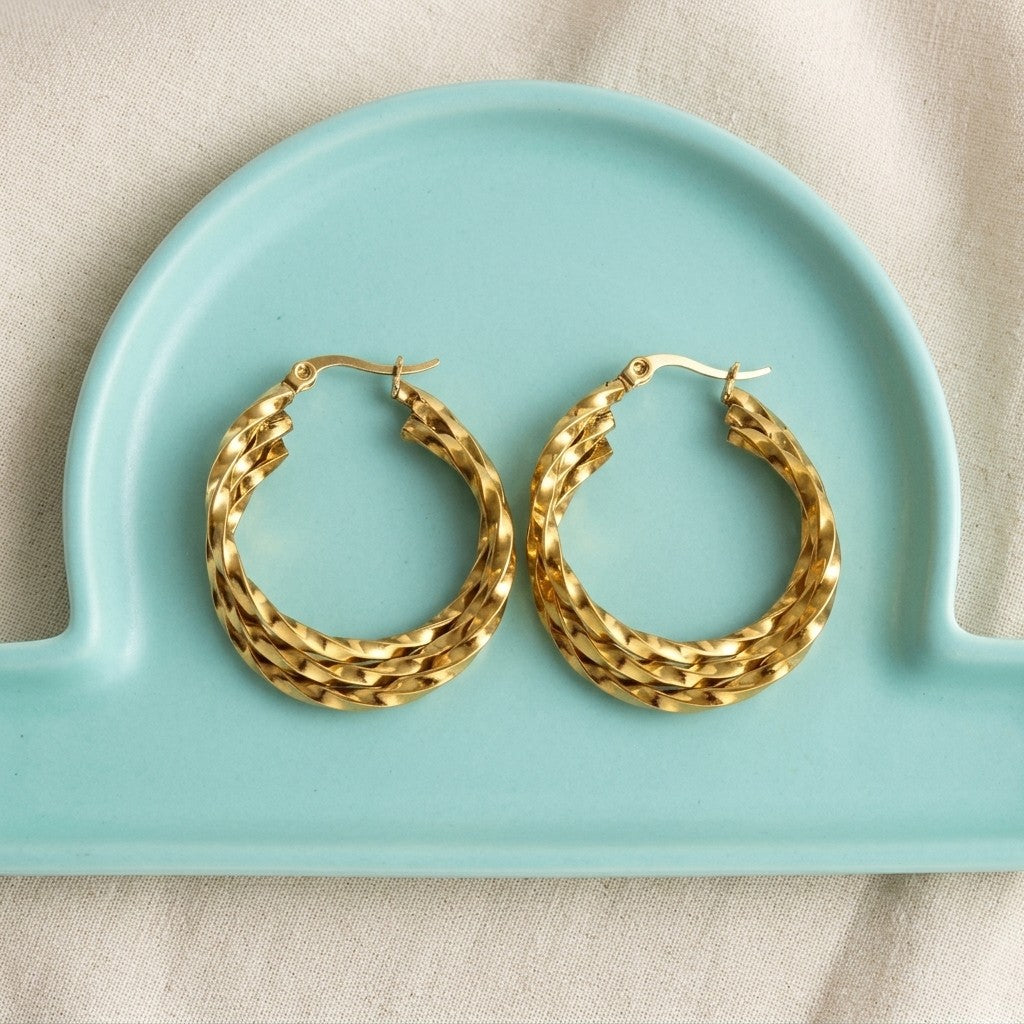 Aramat Jewels gold-tone stainless steel triple twisted hoop earrings, 25mm or 30mm, with a secure hinge closure.