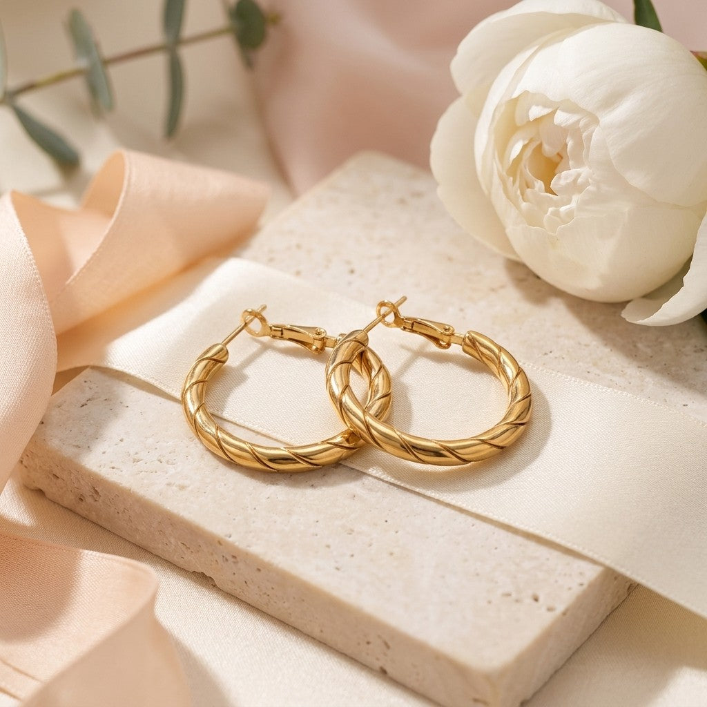 Aramat Jewels gold-tone stainless steel hoop earrings with a twisted rope motif, 25x3.5mm, featuring a clasp closure.
