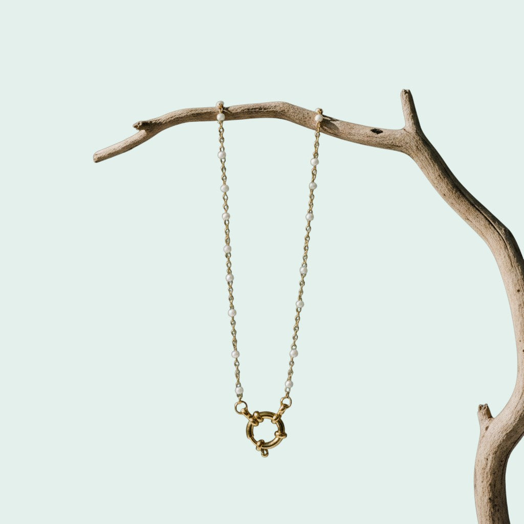 Aramat Jewels gold-tone stainless steel necklace with white enamel beads and a decorative clasp.