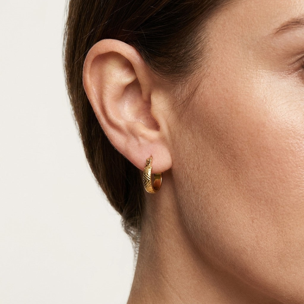 Aramat Jewels small gold-tone stainless steel hoop earrings with a textured zigzag pattern, 10mm diameter.
