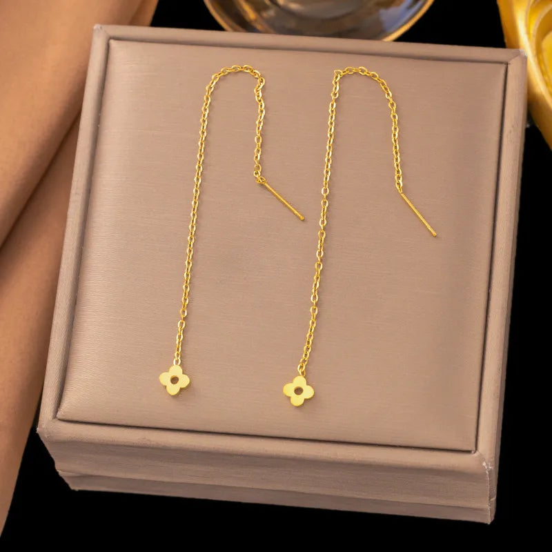 Aramat Jewels goudkleurige RVS doortrek oorbellen met een fijn kettinkje en een bloemvormig detail van 8 cm lang.
