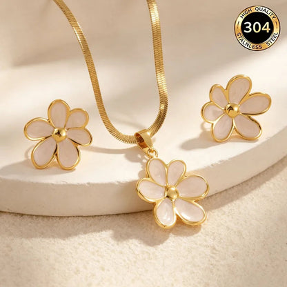 Aramat Jewels goudkleurige RVS sieradenset met witte emaille bloemhanger en bijpassende oorstekers op een witte ondergrond