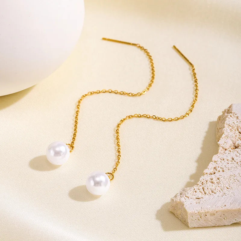 Aramat Jewels goudkleurige doortrek oorbellen van RVS met een elegante witte synthetische parel aan een fijn kettinkje.