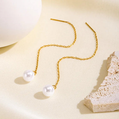 Aramat Jewels goudkleurige doortrek oorbellen van RVS met een elegante witte synthetische parel aan een fijn kettinkje.