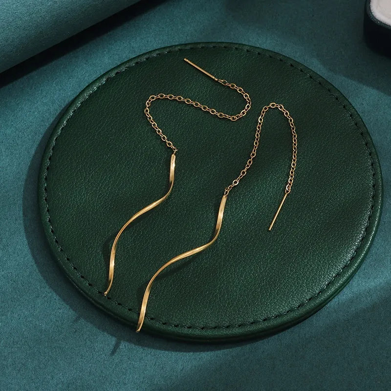 Aramat Jewels goudkleurige doortrek oorbellen van RVS met een elegant gedraaide staaf en fijn kettinkje