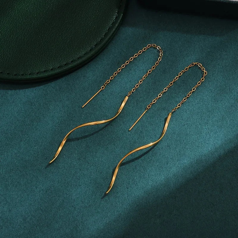 Aramat Jewels goudkleurige doortrek oorbellen van RVS met een elegant gedraaide staaf en fijn kettinkje.