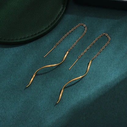 Aramat Jewels goudkleurige doortrek oorbellen van RVS met een elegant gedraaide staaf en fijn kettinkje.
