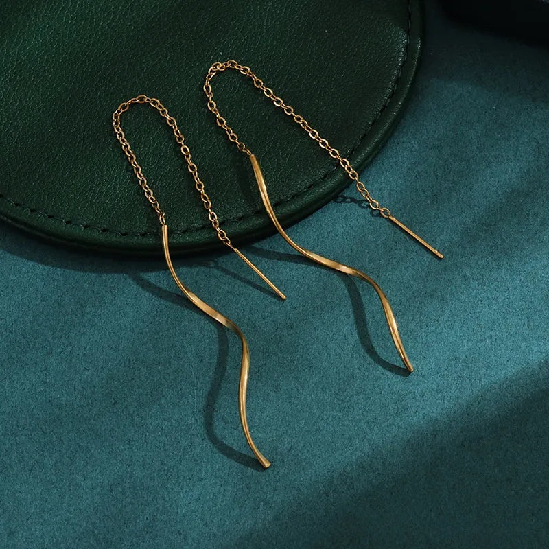 Aramat Jewels goudkleurige doortrek oorbellen van RVS met een elegant gedraaide staaf en fijn kettinkje.