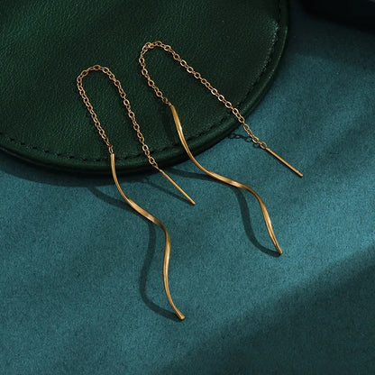 Aramat Jewels goudkleurige doortrek oorbellen van RVS met een elegant gedraaide staaf en fijn kettinkje.