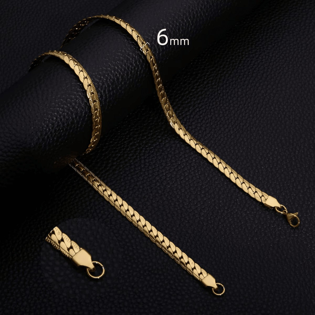 Aramat Jewels 6mm goudkleurige stalen gourmet ketting met bewerkte rand op een zwarte lederen achtergrond