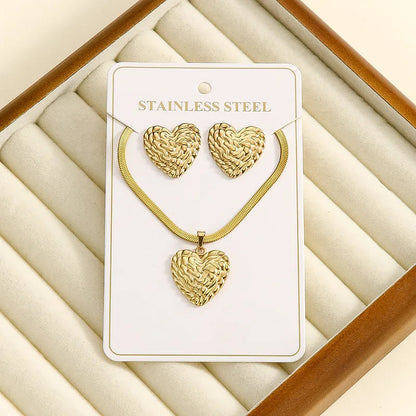 Aramat Jewels goudkleurige sieradenset van RVS met een bewerkte hartvormige hanger aan een platte slangenketting en oorbellen.