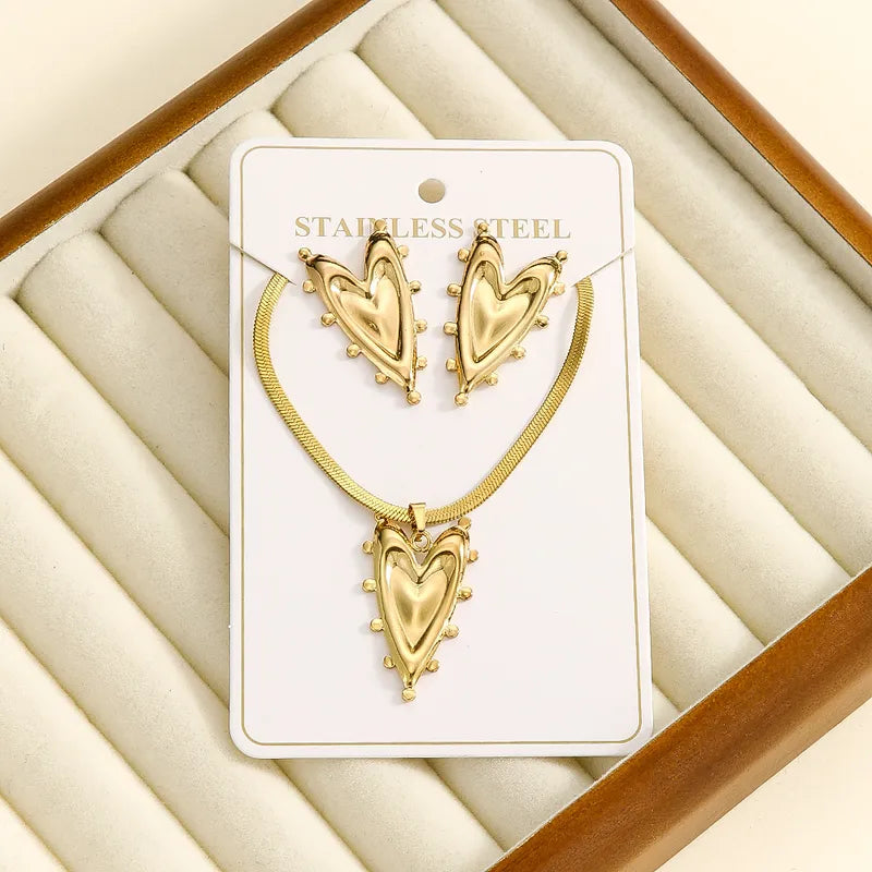 Aramat Jewels goudkleurige RVS sieradenset met hartvormige hanger en oorbellen voorzien van een speels bolletjespatroon.