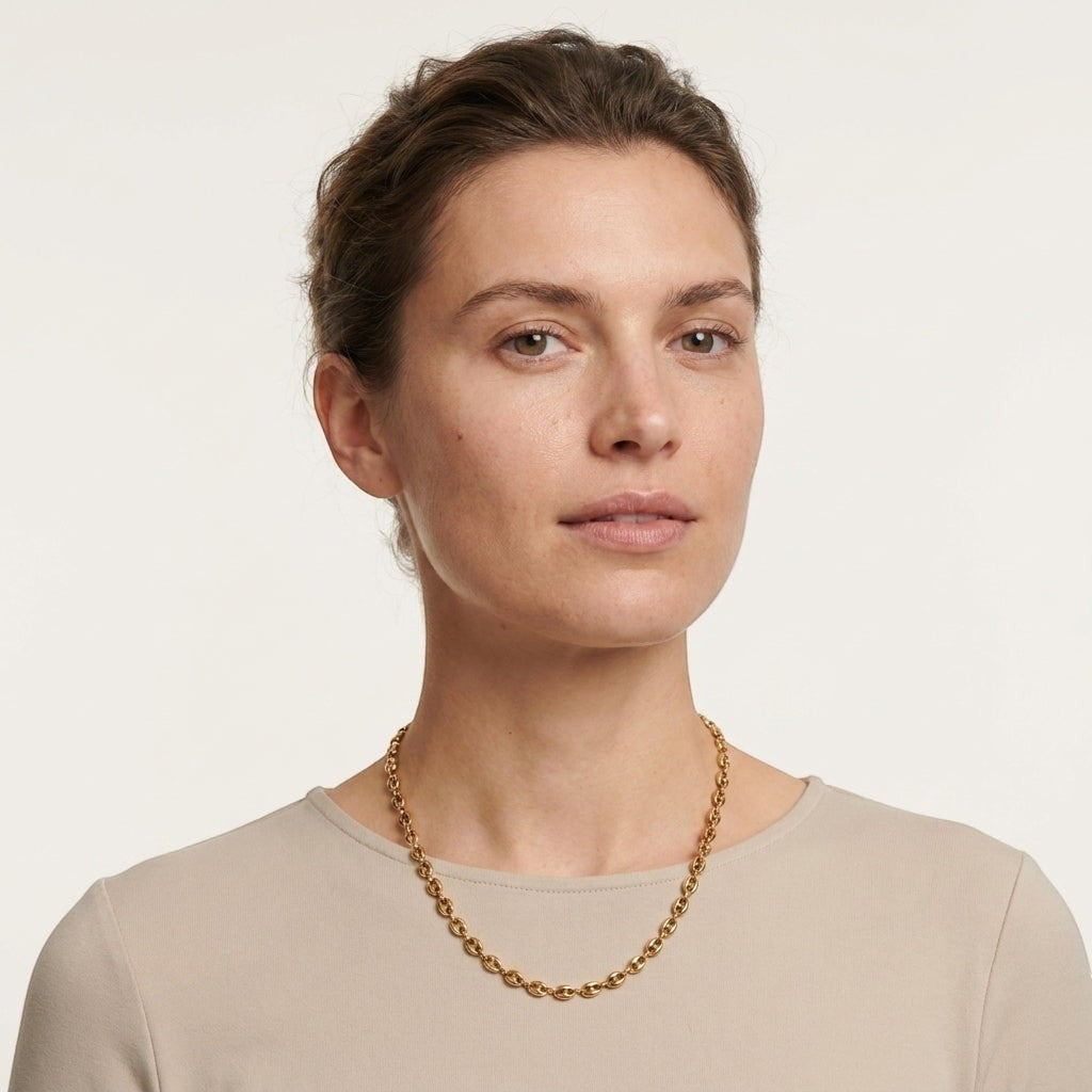 Model draagt een goudkleurige Aramat Jewels koffieboon ketting van 4,5mm breed, gemaakt van duurzaam roestvrij staal.