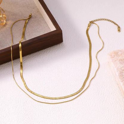 Aramat Jewels goudkleurige 2-in-1 layer ketting van RVS met een slangenketting en een platte visgraatketting.