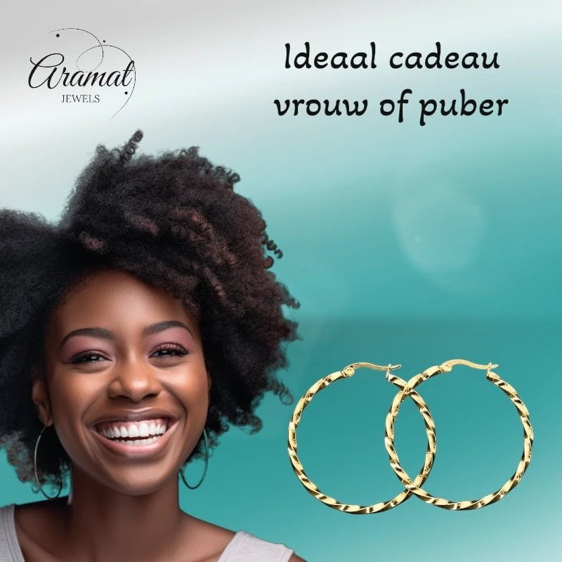 Aramat Jewels goudkleurige RVS swirl hoepeloorbellen van 30 mm met scharniersluiting, gedragen door een lachende vrouw met afro haar.