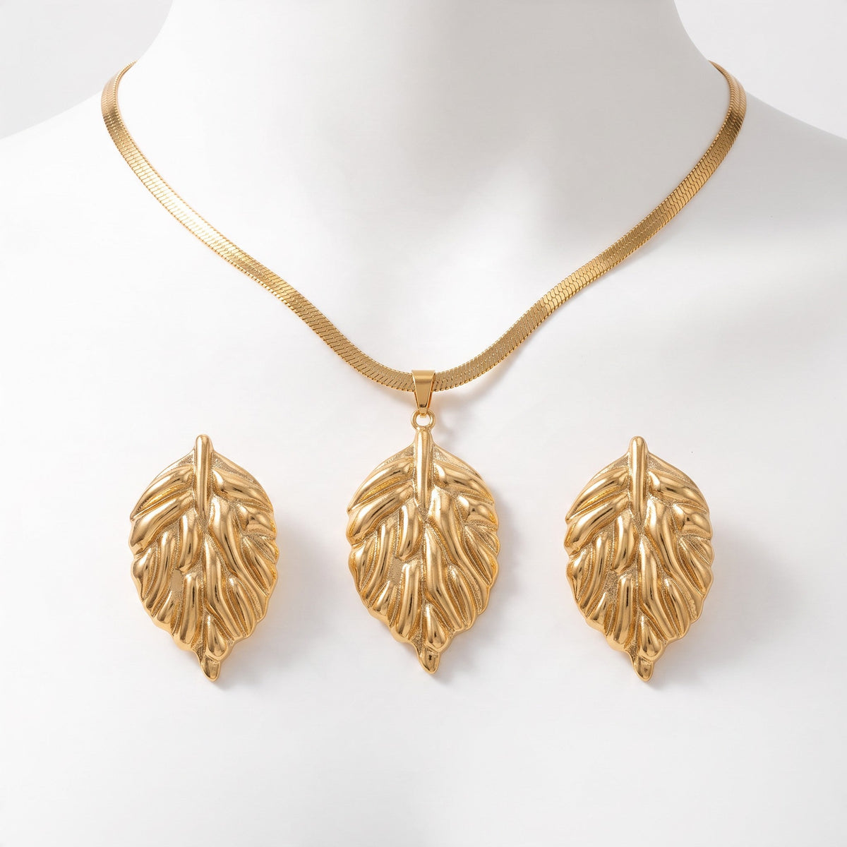 Aramat Jewels goudkleurige RVS sieradenset met een slangenketting en bijpassende bladvormige oorbellen op een buste.