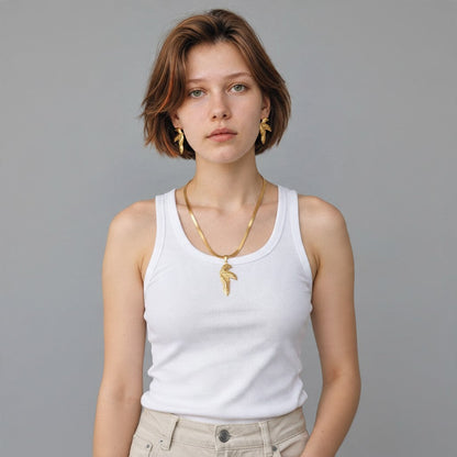Aramat Jewels goudkleurige RVS sieradenset met half blad hanger en bijpassende oorbellen gedragen door een model.