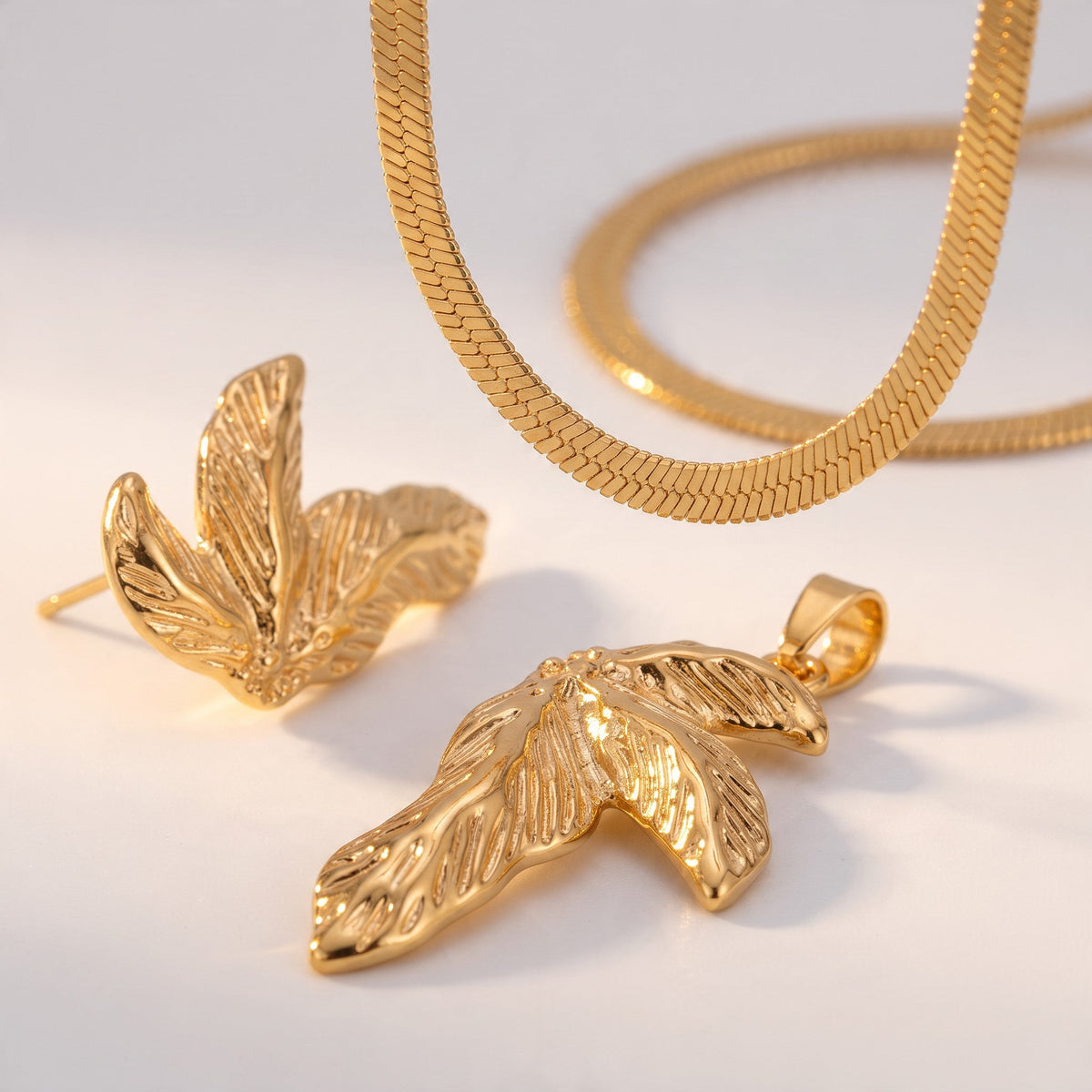 Aramat Jewels goudkleurige RVS sieradenset met een slangenketting en oorbellen in een elegant half blad ontwerp.