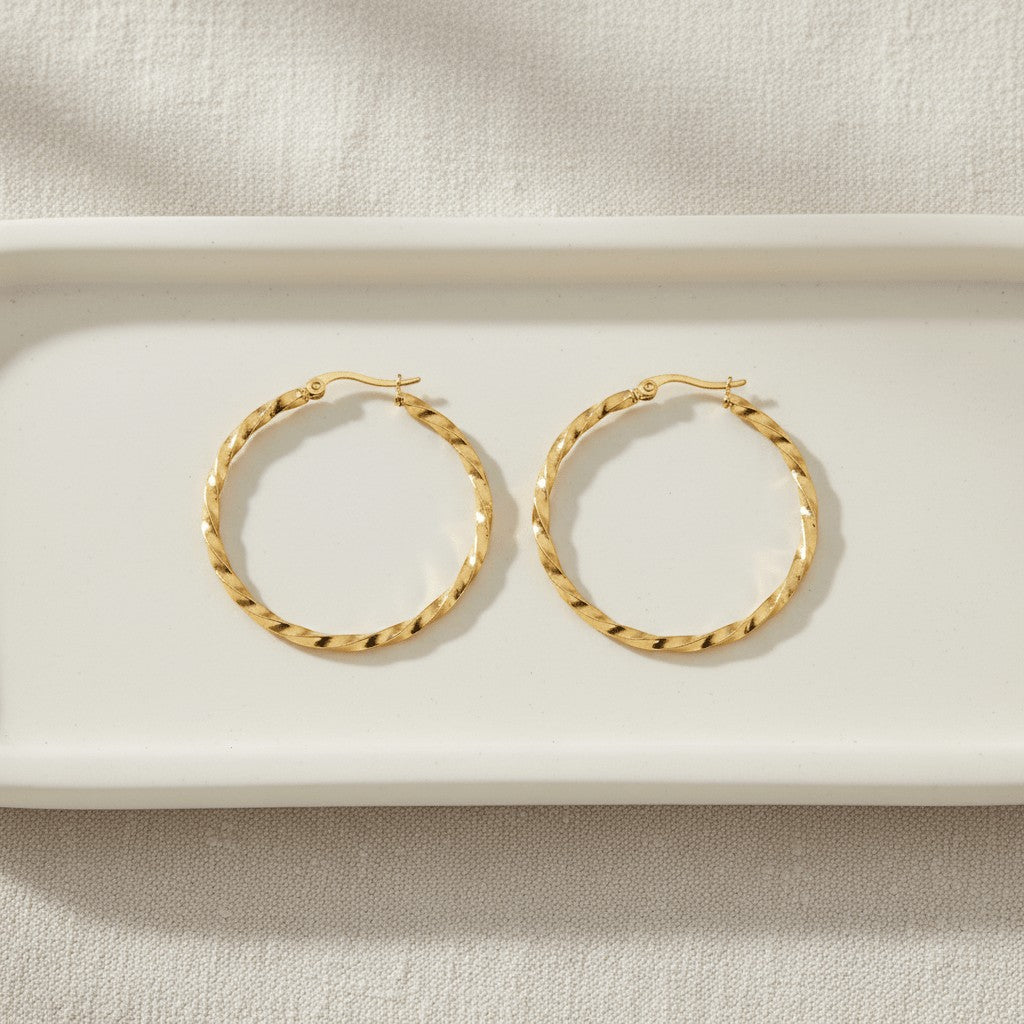 Aramat Jewels Goudkleurige RVS swirl hoepeloorbellen 30 mm met scharniersluiting.