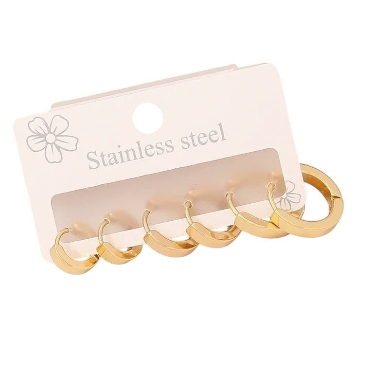 Aramat Jewels goudkleurige stainless steel huggie oorringen set in drie verschillende maten op een displaykaart.
