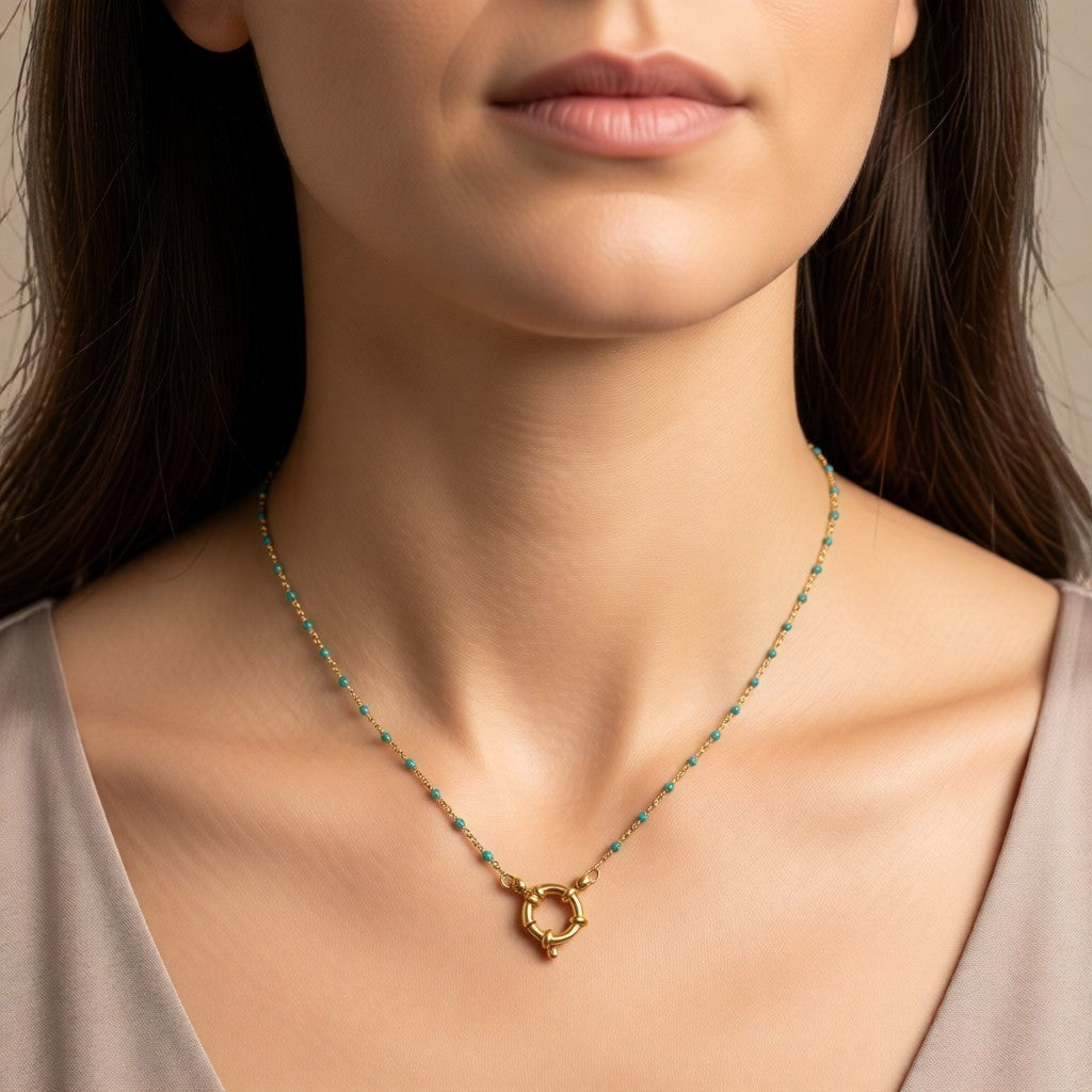 Aramat Jewels gold-tone stainless steel necklace with small green enamel beads and a circular clasp.