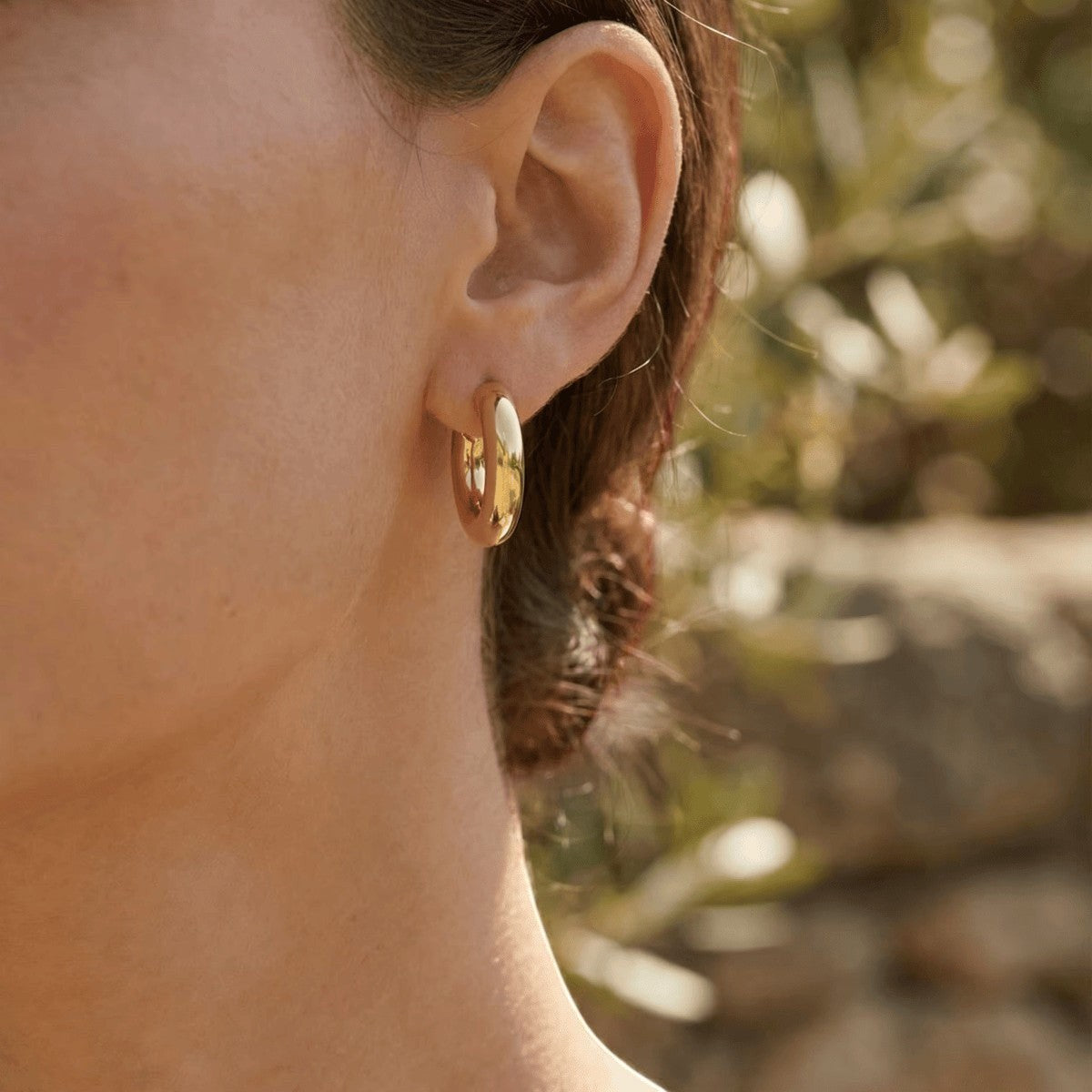 Aramat Jewels massieve gouden halve oorringen van 25x8mm, glad en tijdloos design, gedragen door een model.
