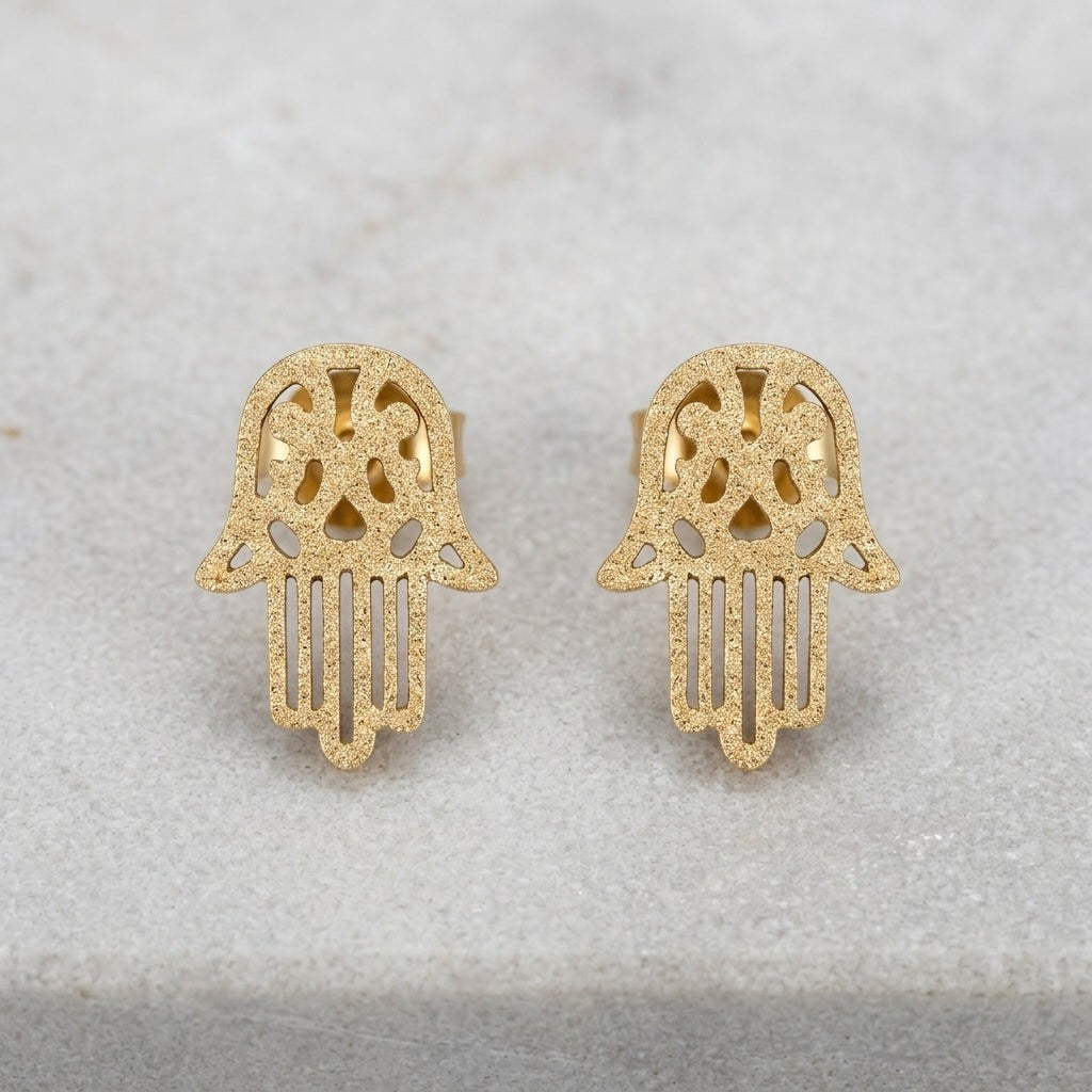 Aramat Jewels goudkleurige Hamsa oorstekers van RVS met een matte sandblasted afwerking in de vorm van een handje.