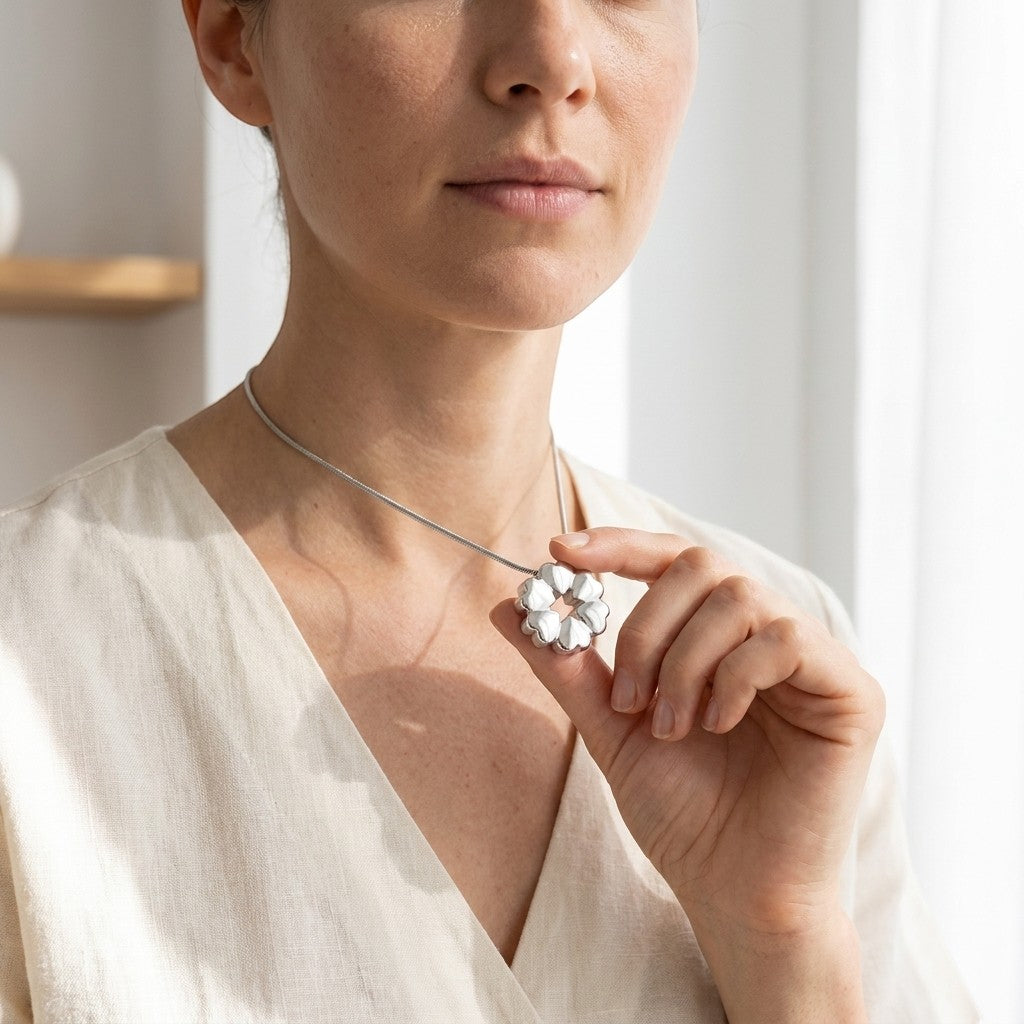 Aramat Jewels circular cremation pendant with heart details, made of stainless steel, worn by a woman.