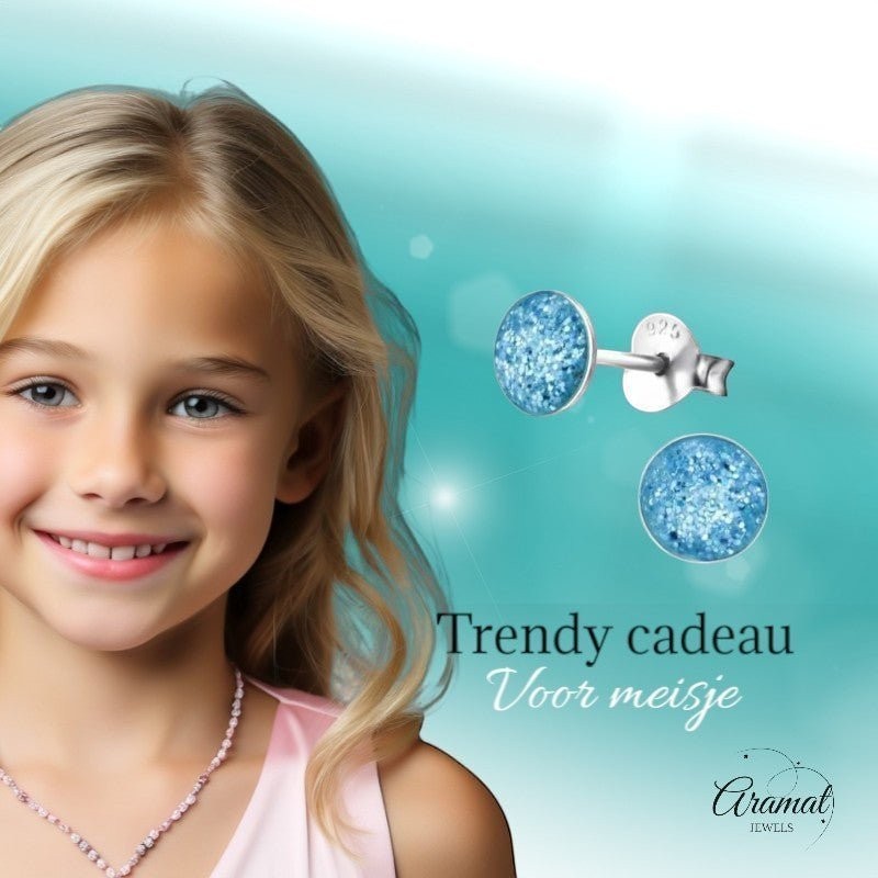 Aramat Jewels 925 zilveren kinderoorbellen met blauwe glitter, rond, 5mm. Een lachend meisje met blonde haren draagt een roze ketting.